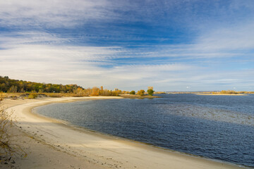 Wide Dnieper River flowing near Kaniv in Ukraine on a sunny autumn day, featuring a sandy beach and calm waters that create a serene and picturesque landscape
