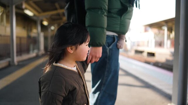 駅で電車を待つお父さんと小さな娘