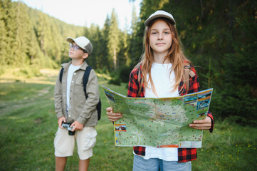Young explorers consulting map during hiking trip in forest