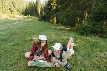 Young hikers consulting map in forest meadow