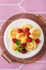 cottage cheese pancakes with raspberries and mint on pink background