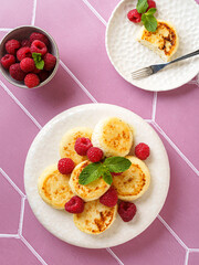 cottage cheese pancakes with raspberries and mint on pink background