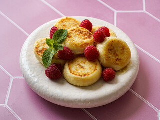 cottage cheese pancakes with raspberries and mint on pink background