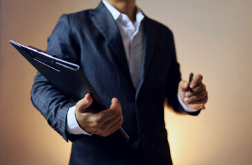 A businessman or manager standing holding a file and a pen represents leadership and ready to solve...