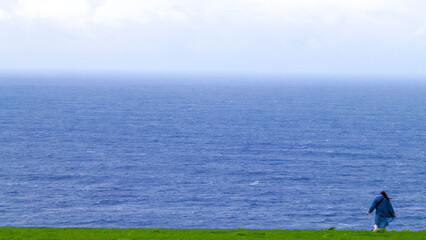 Fototapeta premium Woman traveler on cliff enjoying view of Atantic Ocean.