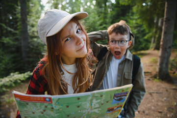Young explorers getting lost while hiking in woods consulting map