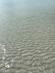 Transparent shallow water with rippled surface and sun reflections creating a serene and calming visual.