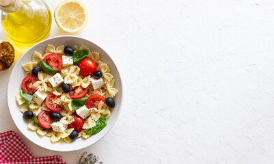Pasta salad with farfalle, tomatoes, cheese, olives and basil. Italian cuisine. Vegetarian food.