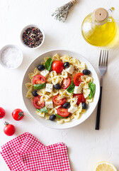 Pasta salad with farfalle, tomatoes, cheese, olives and basil. Italian cuisine. Vegetarian food.