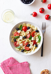 Pasta salad with farfalle, tomatoes, cheese, olives and basil. Italian cuisine. Vegetarian food.