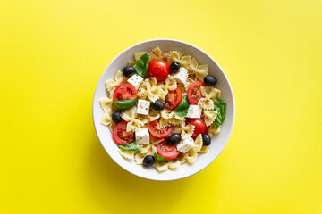 Pasta salad with farfalle, tomatoes, cheese, olives and basil. Italian cuisine. Vegetarian food.
