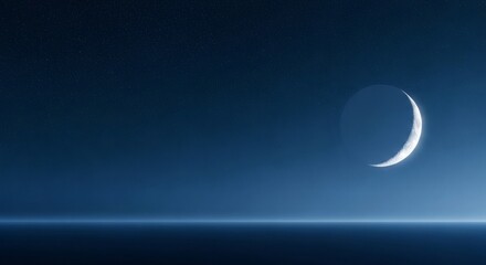 Obraz premium Crescent moon over a dark horizon with faint stars