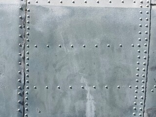 Close-up of weathered aircraft metal fuselage with rivets and panel seams, useful for illustrating aviation engineering, industrial textures, aircraft construction, vintage airplane restoration, and m
