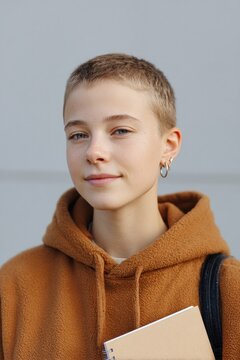 Confident youth with short hair in cozy brown hoodie, holding no