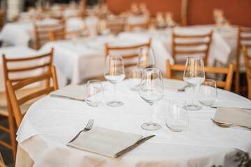 Empty round restaurant table set for guests - white tablecloth and clean dishes