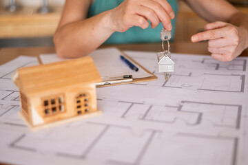 Real estate agent showing house keys and pointing at a specific room on a blueprint with a...