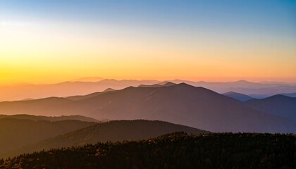 A vast panorama of mountain ranges bathed in the warm hues of a serene sunrise.