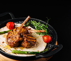 Grilled lamb chops served with vegetables on a sizzling platter