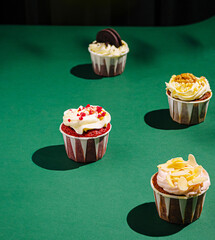 Delicious colorful cupcakes arranged on a green surface in a creative display