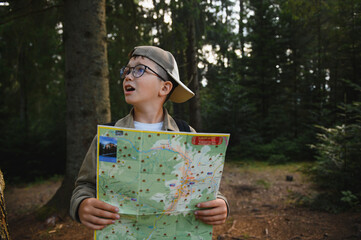 Lost boy scout hiking and reading map in forest