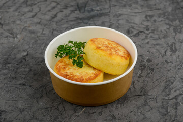 Two potato patties in a disposable plate on a gray background macro