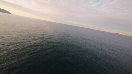 FPV flight over calm Ligurian sea at sunset, wide ocean views, golden light and peaceful horizon.