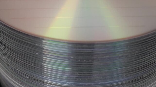 Close-up of stacked DVDs showing reflective rainbow colors on surface