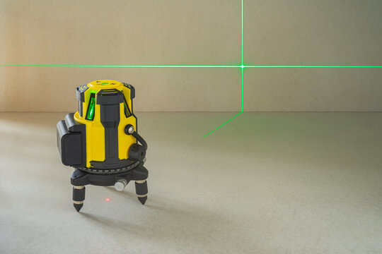 Yellow laser level machine equipment with the green laser lines shown cross lines on floor and wall