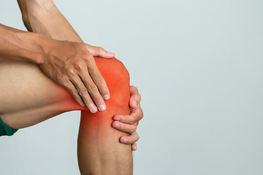 Close-up of a man touching his painful knee highlighted in red, showing symptoms of joint pain or inflammation. Useful for health, medical, and physiotherapy content. Arthritis and tendon problems.