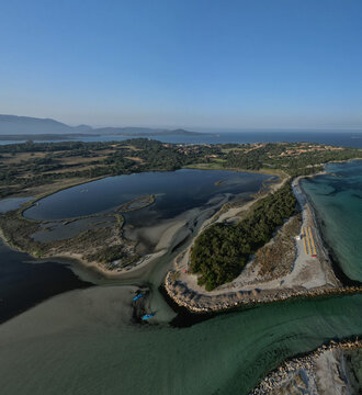 Aerial view of turquoise waters meet the sandy shore, blending into the deep blue of the lagoon near Spiaggia di Porto Pollo, Sardinia, Italy.
