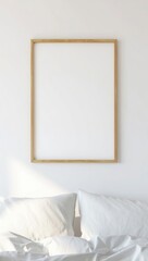 Blank wooden framed picture hanging above a bed with pillows