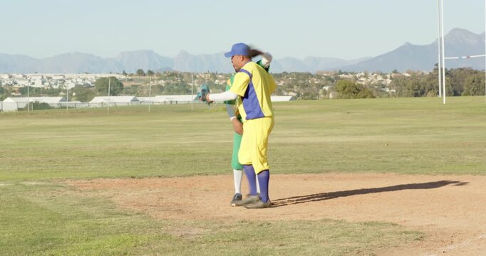 Male baseball players stepping on bag, fist bumping after call out on field showing sportsmanship