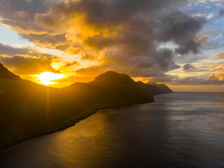 Aerial view of the rugged coastline of Kalsoy island meeting the dark sea under a dramatic sunset sky, Fjords, Northern Isles, Faroe Islands.