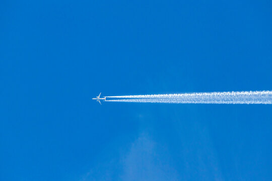 Airplane flying with contrail in blue sky