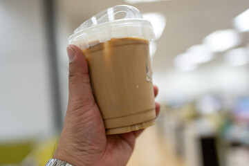 Cold brewed ice latte coffee on plastic cup on hand