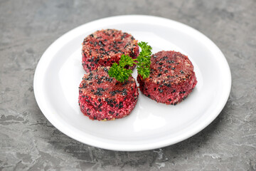 beetroot cutlets in a white plate on a gray concrete background