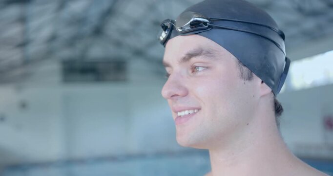 Male swimmer spotting lanes, turning head during sports training, smiling, adjusting goggles