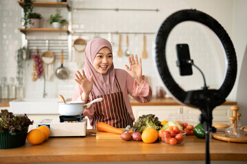 Happy Muslim use mobile phone for live stream about cooking in modern Kitchen