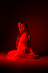 Elegant dancer in red lighting poses gracefully on stage during a performance at night