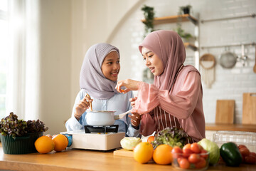 Happy Muslim mother and her daughter preparing a meal in modern Kitchen