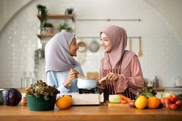 Happy Muslim mother and her daughter preparing a meal in modern Kitchen