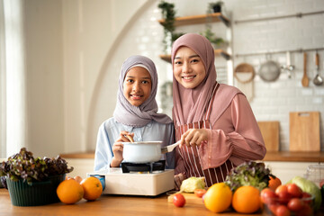 Portrait Of Muslim mother and her daughter preparing a meal in modern Kitchen