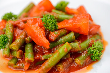 stewed asparagus beans with tomatoes in a white plate