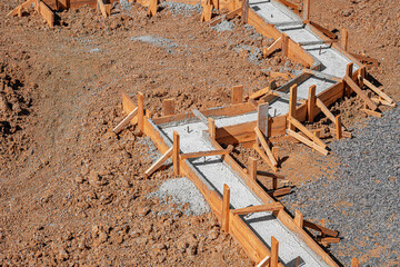 A building foundation with wooden formwork filled with fresh concrete is shown on a construction...