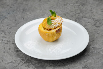 Whole baked apple dessert in a white plate on a concrete gray background