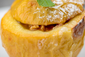 Whole baked apple dessert in a white plate on a gray background macro photo