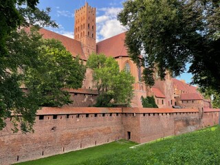 A brick wall with a red roof and a tower in the background