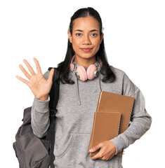 Young Filipino female student with books smiling cheerful showing number five with fingers.