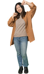 Full-body young Chinese woman celebrating a special day, jumps and raise arms with energy.