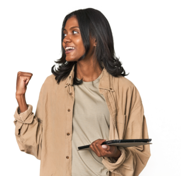 Young Indian woman with digital tablet points with thumb finger away, laughing and carefree. - Powered by Adobe